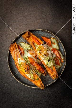 Nutrient-rich eggs baked inside sweet potatoes sit on a rustic plate. Fresh microgreens add a touch of bright color to this healthy meal served in a warm kitchen Nutrient-rich eggs baked inside sweet potatoes sit on a rustic plate. Fresh microgreens add a touch of bright color to this healthy meal served in a warm kitchen 140955003