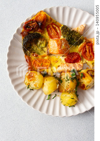 Baked potatoes are served with salmon, broccoli, and tomatoes on a plate. This meal is a good option for breakfast or lunch, offering a balance of nutrition and taste Baked potatoes are served with salmon, broccoli, and tomatoes on a plate. This meal is a good option for breakfast or lunch, offering a balance of nutrition and taste 140955005