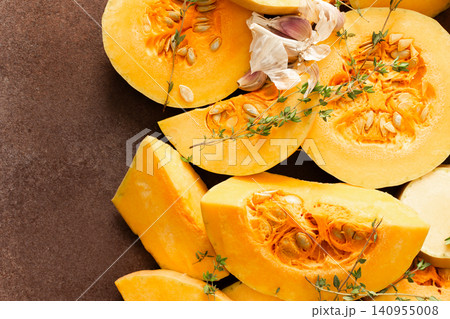 Pumpkin slices are arranged on a kitchen counter with fresh herbs nearby. The scene shows the preparation of seasonal dishes in the fall Pumpkin slices are arranged on a kitchen counter with fresh herbs nearby. The scene shows the preparation of seasonal dishes in the fall 140955008