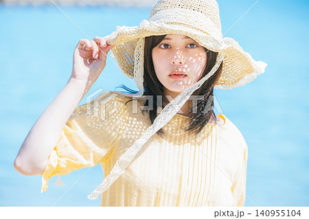 麦わら帽子をかぶって海辺に佇む美しい女性のポートレート 麦わら帽子をかぶって海辺に佇む美しい女性のポートレート 140955104
