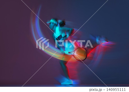 Female tennis player serving with colorful light trails in dynamic studio portrait. Female tennis player serving with colorful light trails in dynamic studio portrait. 140955111
