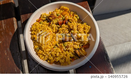 Paella with seafood and vegetables, traditional Spanish rice dish in a bowl on the wooden bench Paella with seafood and vegetables, traditional Spanish rice dish in a bowl on the wooden bench 140955726