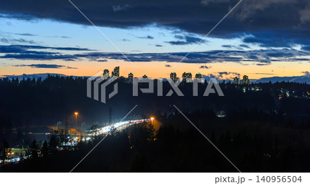 Twilight City Skyline with Highway Traffic Light Trails and Silhouetted Trees Twilight City Skyline with Highway Traffic Light Trails and Silhouetted Trees 140956504