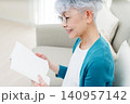 ソファに座って本を読むシニア女性 140957142