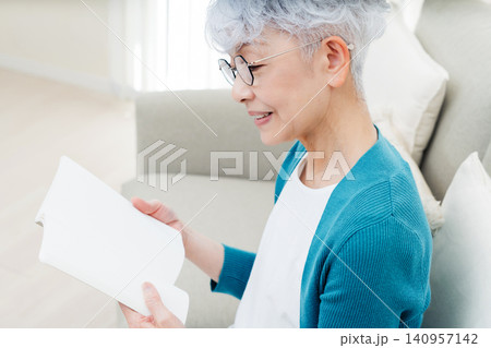ソファに座って本を読むシニア女性 140957142