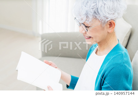 ソファに座って本を読むシニア女性 140957144