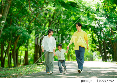 手を繋いで公園を歩く三人家族 手を繋いで公園を歩く三人家族 140957792