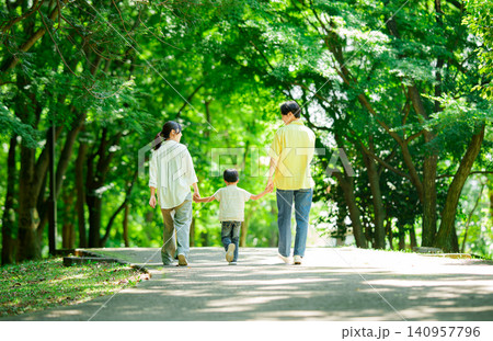 手を繋いで公園を歩く三人家族 手を繋いで公園を歩く三人家族 140957796