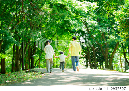 手を繋いで公園を歩く三人家族	 140957797