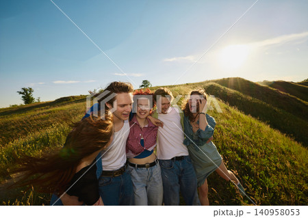 Happy friends embracing at sunset on grassy countryside hillside. Happy friends embracing at sunset on grassy countryside hillside. 140958053