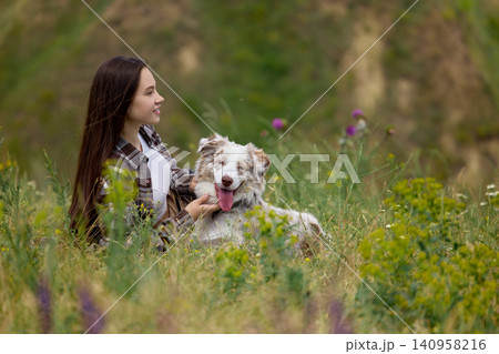 Woman relaxing with happy dog in tall summer meadow Woman relaxing with happy dog in tall summer meadow 140958216