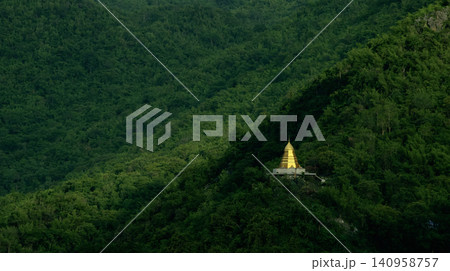 Golden Buddhist Pagoda Nestled on a Lush Green Tropical Mountain Golden Buddhist Pagoda Nestled on a Lush Green Tropical Mountain 140958757