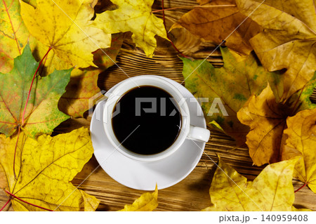 Cup of coffee and autumn maple leaves on wooden table. Top view. Autumn concept Cup of coffee and autumn maple leaves on wooden table. Top view. Autumn concept 140959408