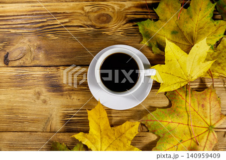 Cup of coffee and autumn maple leaves on wooden table. Top view. Autumn concept 140959409