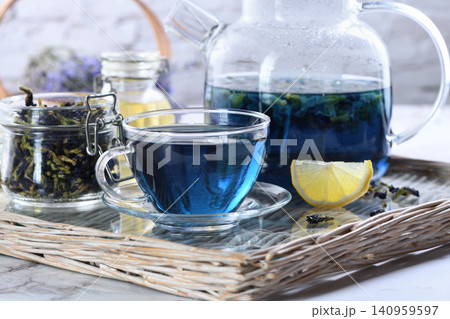 Blue butterfly pea flower tea in glass teapot and cup on wicker tray Blue butterfly pea flower tea in glass teapot and cup on wicker tray 140959597