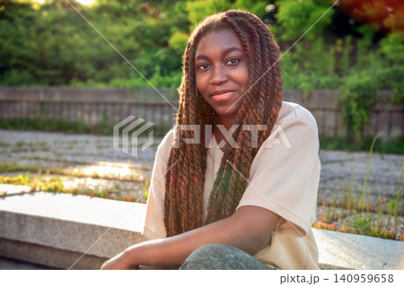 Fabulous outdoor portrait of a young Black university student sitting on sunlit campus steps Fabulous outdoor portrait of a young Black university student sitting on sunlit campus steps 140959658