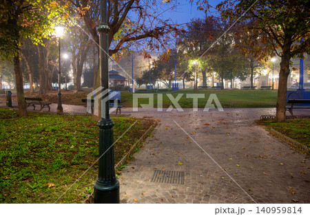 Turin, piedmont, italy. November 20, 2024. Giardini reali park in turin's historic center at dusk during autumn, with street lights illuminating trees and misty atmosphere Turin, piedmont, italy. November 20, 2024. Giardini reali park in turin's historic center at dusk during autumn, with street lights illuminating trees and misty atmosphere 140959814