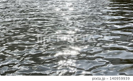 Scenery surface of pond illuminated by sun at summertime. Calm view on sea with small waves at sunny day. Beautiful summer nature landscape. Concept of tranquility scene. Slow motion Scenery surface of pond illuminated by sun at summertime. Calm view on sea with small waves at sunny day. Beautiful summer nature landscape. Concept of tranquility scene. Slow motion 140959939