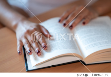 Woman reading an open book at a wooden table, engaging in study and education, absorbing information and knowledge for personal development and literacy Woman reading an open book at a wooden table, engaging in study and education, absorbing information and knowledge for personal development and literacy 140960059