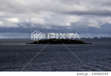 Wind Turbines Stand on an Island in the Ocean Under a Cloudy Sky in Denmark 140960344