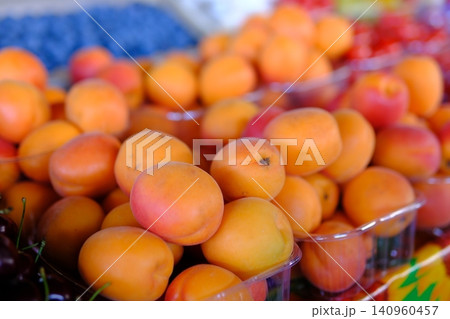 Fresh ripe apricots in plastic containers at local market showcasing sweet seasonal fruit and summer farm harvest Fresh ripe apricots in plastic containers at local market showcasing sweet seasonal fruit and summer farm harvest 140960457