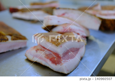 market pork lard. Stack of thick sliced cured pork belly with visible fat layers and rind texture arranged for sale as traditional spanish food product in local market setting market pork lard. Stack of thick sliced cured pork belly with visible fat layers and rind texture arranged for sale as traditional spanish food product in local market setting 140960507