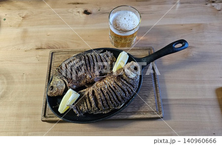Tasty roasted crucian carp fish served with beer on black table, flat lay. Homemade seafood dish 140960666
