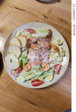 Caesar salad Traditional caesar salad in a white bowl with leaves and a sauce boat and parmesan. Selected focus Caesar salad Traditional caesar salad in a white bowl with leaves and a sauce boat and parmesan. Selected focus 140960713