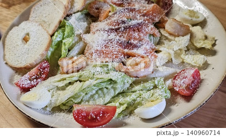 Caesar salad Traditional caesar salad in a white bowl with leaves and a sauce boat and parmesan. Selected focus Caesar salad Traditional caesar salad in a white bowl with leaves and a sauce boat and parmesan. Selected focus 140960714