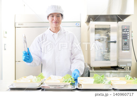 弁当工場で盛り付け作業を行う白衣姿の若い男性 140960717