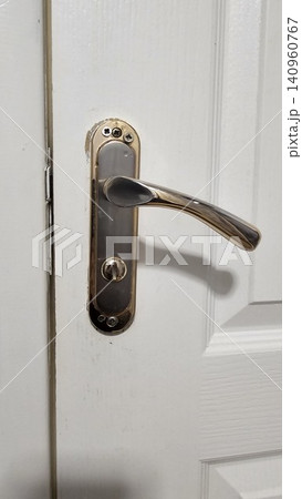 Close-up of a classic silver door handle and lock on a white wooden door. Ideal for home decor, interior design inspiration, or architectural details. Close-up of a classic silver door handle and lock on a white wooden door. Ideal for home decor, interior design inspiration, or architectural details. 140960767