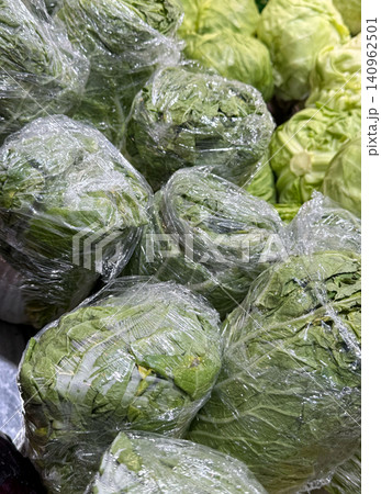 Plastic-wrapped cabbages bin Chinese cabbage in the store wrapped in plastic. Cabbage for sale vegetable market. Vegetables. Products at the market. Close-up of Chinese cabbage on a shelf in a store 140962501