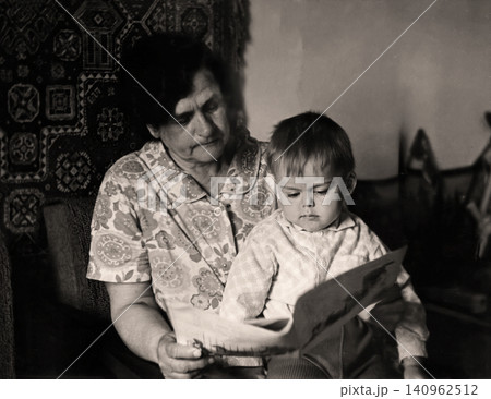 Grandmother Reading with Her Young Grandson Indoors, Vintage Family Portrait Grandmother Reading with Her Young Grandson Indoors, Vintage Family Portrait 140962512