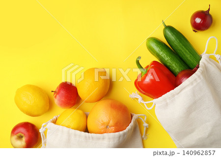 Cotton eco bags with fruits and vegetables on yellow background, flat lay. Space for text Cotton eco bags with fruits and vegetables on yellow background, flat lay. Space for text 140962857