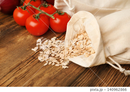 Cotton eco bags with vegetables and oat flakes on wooden table, closeup Cotton eco bags with vegetables and oat flakes on wooden table, closeup 140962866