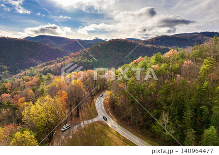 Scenic drive through Tennessee Appalachians at sunset in fall season. Car traveling on curvy forest road under vibrant autumn foliage Scenic drive through Tennessee Appalachians at sunset in fall season. Car traveling on curvy forest road under vibrant autumn foliage 140964477
