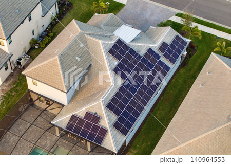 Aerial view of American home roof with blue solar photovoltaic panels for producing clean ecological electric energy. Renewable electricity with zero emission concept Aerial view of American home roof with blue solar photovoltaic panels for producing clean ecological electric energy. Renewable electricity with zero emission concept 140964553