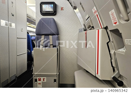 Flight Attendant Jump Seat and Emergency Exit Door Inside Airplane Cabin. 140965342