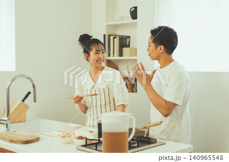 身振りを交えて楽しく話す男性と笑顔で聞く女性のキッチン会話シーン 身振りを交えて楽しく話す男性と笑顔で聞く女性のキッチン会話シーン 140965548