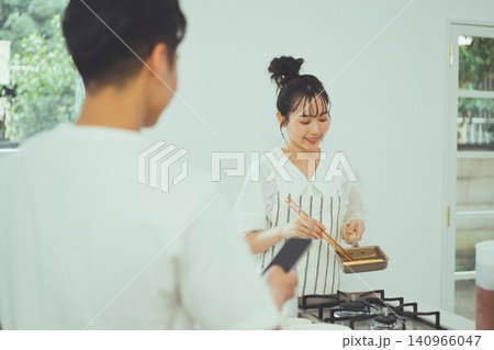 男性の前で玉子焼きを丁寧に作っている女性のキッチンシーン 男性の前で玉子焼きを丁寧に作っている女性のキッチンシーン 140966047