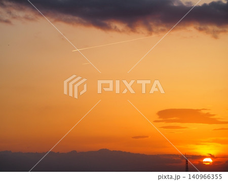 飛行機雲が残るオレンジ色の夕焼け空 飛行機雲が残るオレンジ色の夕焼け空 140966355