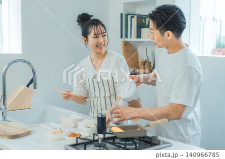 お弁当作り中に向き合って笑顔で会話するカップルのキッチンシーン 140966785