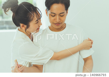 料理をする彼氏に腕を回して甘える彼女 料理をする彼氏に腕を回して甘える彼女 140966793