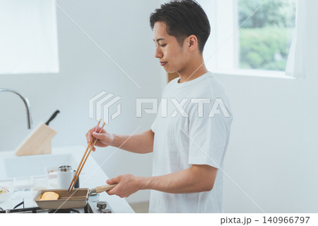 キッチンで玉子焼きを作る若い男性 キッチンで玉子焼きを作る若い男性 140966797