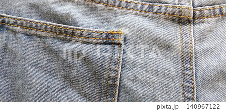 A close-up view of the back pocket of blue denim jeans, showing yellow stitching. A close-up view of the back pocket of blue denim jeans, showing yellow stitching. 140967122