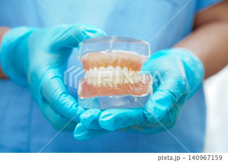 Dentist holding dental implant, artificial tooth roots into jaw, root canal of dental treatment, gum disease, teeth model for dentist. Dentist holding dental implant, artificial tooth roots into jaw, root canal of dental treatment, gum disease, teeth model for dentist. 140967159