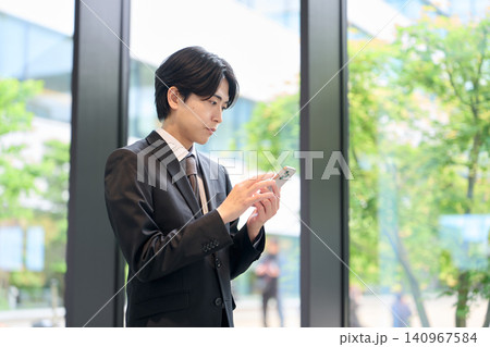 スマートフォンを操作するアジア人ビジネスマン 140967584