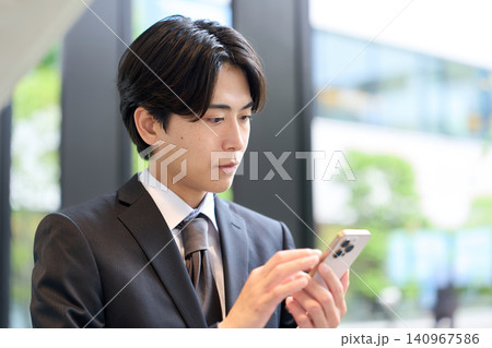 スマートフォンを操作するアジア人ビジネスマン スマートフォンを操作するアジア人ビジネスマン 140967586