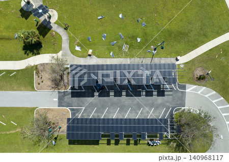 Hurricane wind damage to solar panels installed as shade roof over parking lot for parked electric cars. Failing of photovoltaic technology integrated in urban infrastructure Hurricane wind damage to solar panels installed as shade roof over parking lot for parked electric cars. Failing of photovoltaic technology integrated in urban infrastructure 140968117