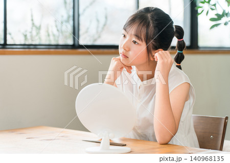 鏡の前で不満そうな表情の小学生,中学生の女の子 140968135